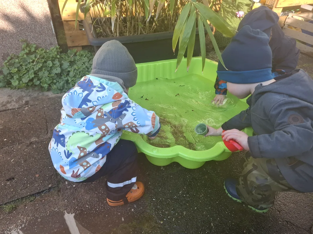 Kinder spielen draußen am Wassertisch